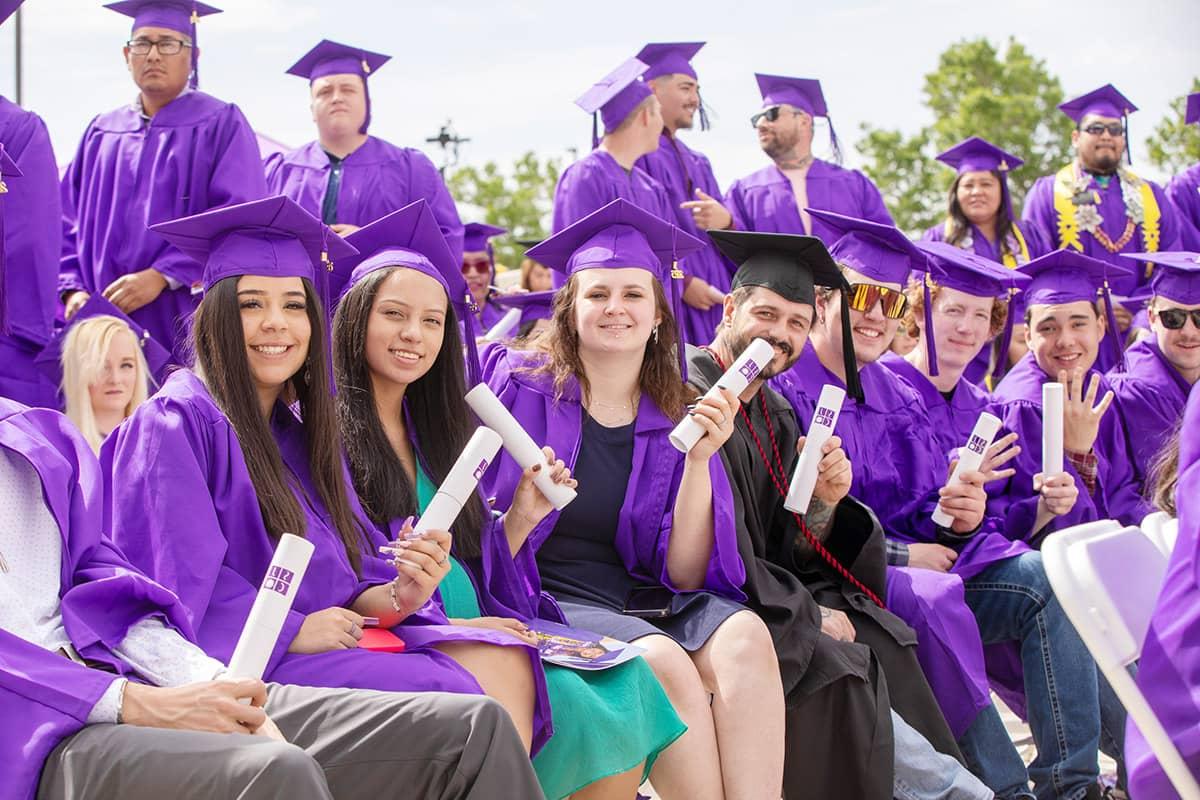 Smiling SJC Graduates wearing cap and gown at graduation.